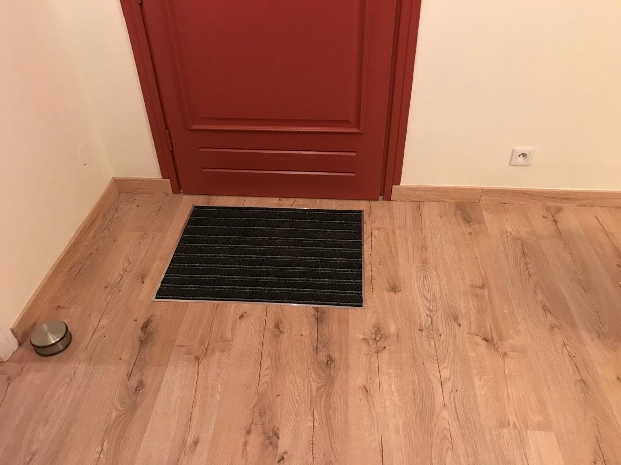 parquet sur carrelage à Frégouville (32490) : entrée finie, parquet flottant chêne et tapis de propreté incrusté devant la porte
