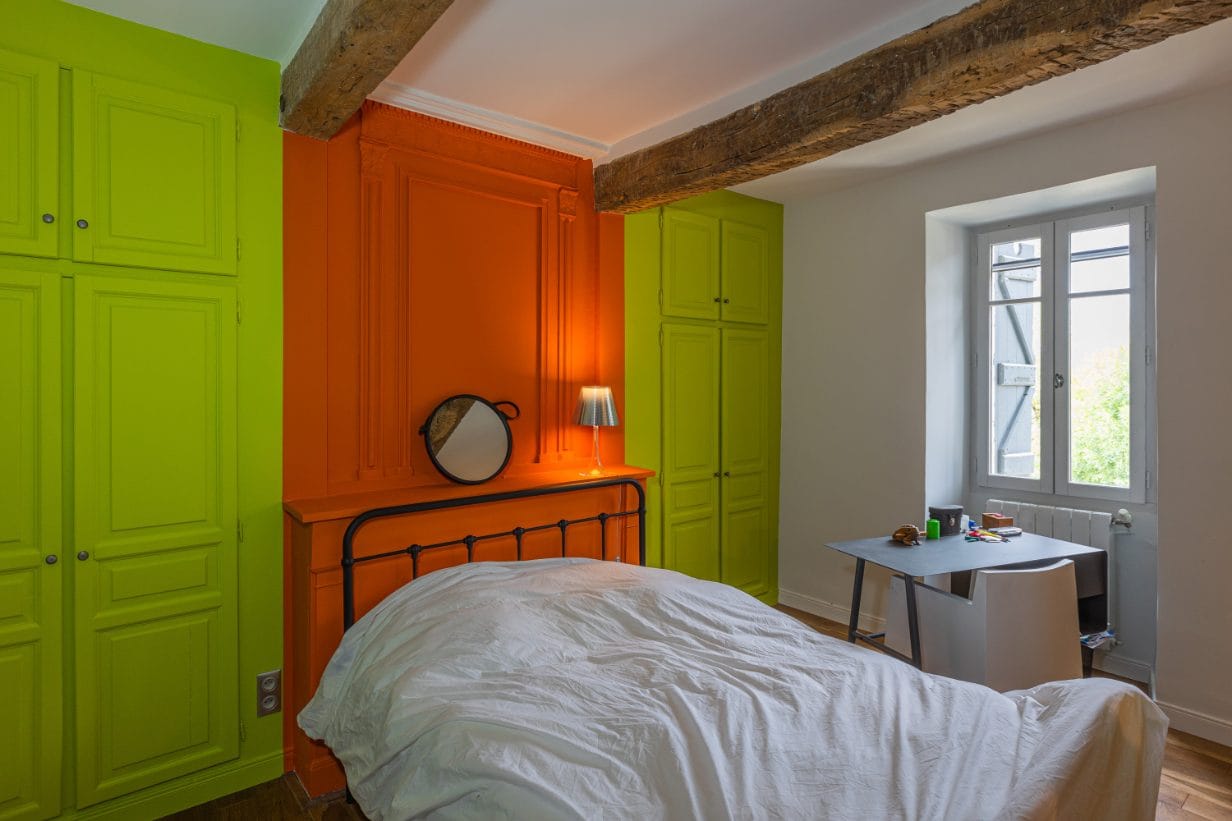 Poutres apparentes dans une chambre - Médale Peinture poutres apparentes en bois brut dans une chambre aux placards vert anis et à la boiserie orange